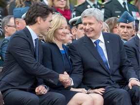 Justin Trudeau shakes hands with Stephen Harper with Laureen Harper in between during a memorial service at the National War Memorial on Thursday as Canada marks the one-year anniversary of the Oct. 22, 2014 attacks on Parliament Hill and at the Cenotaph.