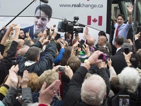 Liberal leader Justin Trudeau waves to a crowd of supporters as he boards his bus during a campaign stop Tuesday, October 13, 2015 in Stratford, Ont.