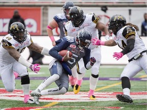 Montreal Alouettes quarterback Kevin Glenn, centre, is surrounded by Hamilton Tiger-Cats' Eric Norwood (40), Bryan Hall (6) and Taylor Reed, right, during first half CFl football action in Montreal, Sunday, October 18, 2015.