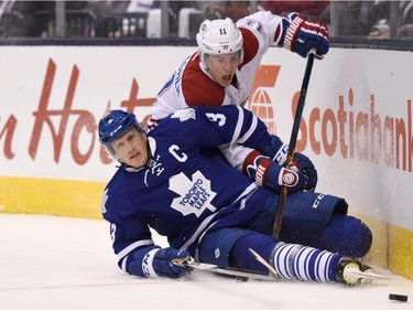 Montreal Canadiens' Brendan Gallagher (11) and Toronto Maple Leafs' Dion Phaneuf battle along the boards during first period NHL action in Toronto on Wednesday, Oct. 7, 2015.