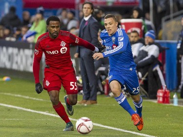 Montreal Impact coach Mauro Biello (rear in suit) watches a battle between his player Donny Toia (right) and Robbie Findley of Toronto FC in the first half of a game at Saputo stadium in Montreal Sunday, Oct. 25, 2015.