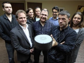 Gilles Ouellet, president of Le Club de Hockey Sonore Les Hiboux de Montréal holds a prototype of a hockey puck that can be used players who are visually impaired, surrounded by the team of designers and engineers from Université du Québec à Montréal who developed it.