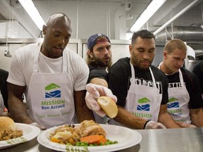 Members of the Alouettes from left:, Kyries Hebert, Nicolas Boulay, Chip Cox, and Samuel Giguère serve a traditional turkey dinner to 300 homeless people at the Welcome Hall Mission in Montreal, Monday October 12, 2015.