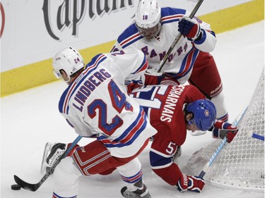 David Desharnais of the Montreal Canadiens is kept away from the puck by Oscar Lindberg and Marc Staal of the New York Rangers in the first period in NHL action at the Canadiens' home opener at the Bell Centre Thursday, October 15, 2015 in Montreal.