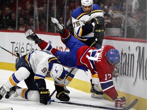 Canadiens' Torrey Mitchell is shoved over Blues' Steve Ott by Blues' Ryan Reaves, rear, during second period in Montreal on Tuesday October 20, 2015.