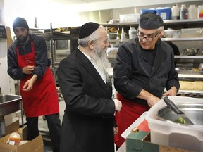 Rabbi Chaim Shlomo Cohen, middle, executive director of the MADA community organization, with volunteer Emile Sabbah, right, in the kitchen where they prepare meals. On the left is volunteer Jeffery Cox.
