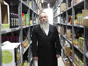Rabbi Chaim Shlomo Cohen, executive director of the MADA community organization, among the shelves filled with food.