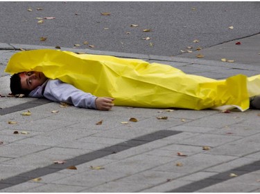 A participant playing the role of a victim lies dead on the sidewalk during a terror attack simulation in Montreal on Saturday, Oct. 24, 2015.