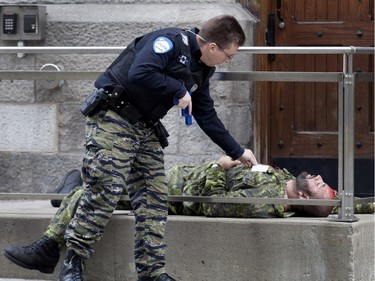 A police officer checks on a victim during a terror attack simulation in Montreal on Saturday, Oct. 24, 2015.