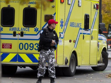 A police officer stands guard as an ambulance attends to victims during a terror attack simulation in Montreal on Saturday, Oct. 24, 2015.
