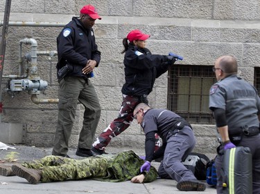 Montreal police pursue a suspect as ambulance staff attend to a victim during a terror attack simulation in Montreal on Saturday, Oct. 24, 2015.