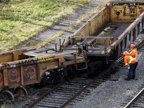A CP Rail crew inspects a derailed train in Montreal on Thursday October 29, 2015. One railway car plunged into the backyard of a residential complex next to the tracks.