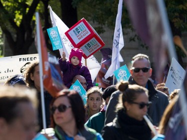 A child rides on a demonstrator's shoulders as they join a crowd estimated at over 100,000 people taking part in coalition of public-sector unions demonstration in Montreal on Saturday, Oct. 3, 2015.