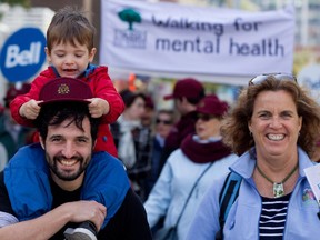 Bruno Collard carries his son Eli as he walks with Helène Brouillet alongside thousands of people marching through the streets on Montreal in support of mental health issues on Sunday October 4, 2015.