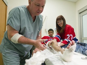 Nurse Pierre Ouellet, left, removes a cast from the leg of Marc-Étienne Pigeon, 18, while Pigeon's mother, Marie-France Boulet, right, watches, at the Shriner's Hospital's new location at the Glen Campus in Montreal, Monday October 5, 2015.  Patients were moved to the new location today for the first time and Pigeon was the first patient to be moved in.
