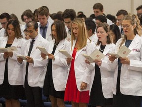 Second-year students in McGill University's Faculty of Medicine, having received their white coats in the faculty's annual "Donning  the Healer's Habit" ceremony in Montreal on Friday, September 25, 2015, reciting the class pledge, which they wrote together. The students received their white coats in a symbolic ceremony marking their passage from lay people to professionals.