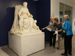 McGill University Health Centre employee Rachel Hawes shows Nancy Woollven, left, and Wendy Heitshu, graduates of the Royal Victoria Hospital nursing class of 1964, the cleaned and restored statue of Queen Victoria in its new location at the Glen site. Hawes is pointing to the toe of one of the children; it had been missing for years.