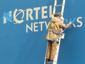 A worker paints in the letters before new signs were hung over old Nortel Networks signs in 2012, signifying the end of an era.
