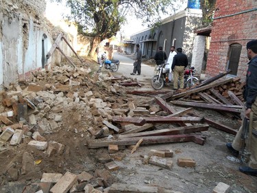 Pakistani policemen stand beside debris of collapsed houses after an earthquake in Kohat on October 26, 2015.