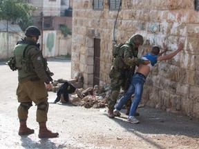 Israeli soldiers search a Palestinian man near the Jewish settlement of Beit Hadassah, in the centre of the Israeli-occupied city of Hebron, on October 29, 2015.