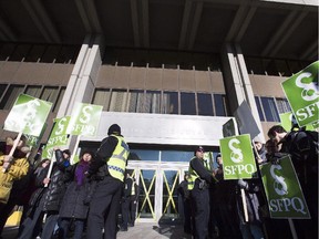 Police officers stands in a corridor to allow non-striking civil servants to walk into a government building Tuesday, October 27, 2015 in Quebec City.