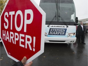 Protestors stand outside the media bus at a event where  Conservative leader Stephen Harper was in Quebec City, Que., Friday, Oct. 16, 2015.