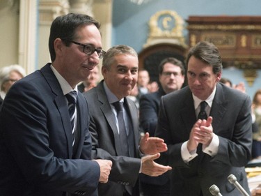 Quebec Opposition MNA Stéphane Bédard, left, is applauded after he announced his decision to resign, as Quebec Opposition Leader Pierre-Karl Peladeau, right, and members of the legislature applaud, Thursday, October 22, 2015 at the legislature in Quebec City. MNA Nicolas Marceau, centre, looks down.