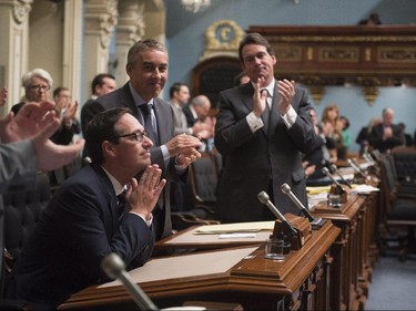 Quebec Opposition MNA Stéphane Bédard, left, joins his hands after he announced his decision to resign, as Quebec Opposition Leader Pierre-Karl Peladeau, right, and members of the legislature applaud, Thursday, October 22, 2015 at the legislature in Quebec City.