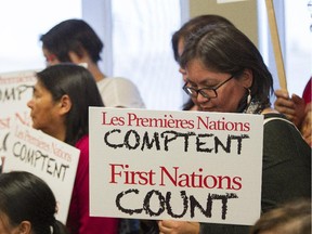 Brenda Michel of the Innu community of Mingan holds a sign at a press conference of Quebec First Nations chiefs who met in Val-d'Or north of Montreal Tuesday, October 27, 2015. They called for an independent inquiry into allegations that Sûreté du Québec officers sexually and physically abused Algonquin women while on duty.