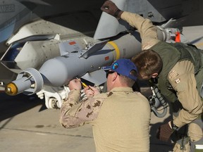 An Air Weapons Systems Technician and a pilot inspect a CF-18 Hornet fighter jet before the next mission at Camp Patrice Vincent during Operation Impact on January 14, 2015.   Prime Minister Justin Trudeau announced yesterday that Canadian air strikes against ISIS would end by Feb. 22.
