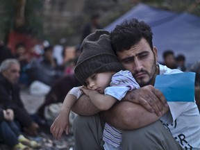A Syrian refugee child sleeps on his father's arms while waiting at a resting point to board a bus, after arriving on a dinghy from the Turkish coast to the northeastern Greek island of Lesbos, Oct. 4, 2015.