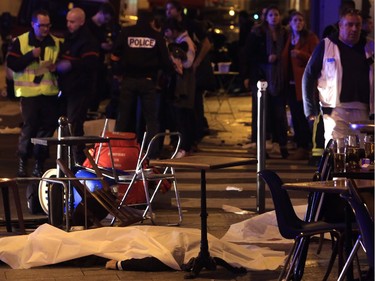 A victim is pictured on the pavement outside a Paris restaurant, Friday, Nov. 13, 2015. Police officials say dozens have been killed in shootouts and other violence around Paris. Police have reported shootouts in at least two restaurants in Paris. At least two explosions have been heard near the Stade de France stadium, and French media is reporting of a hostage-taking in the capital.