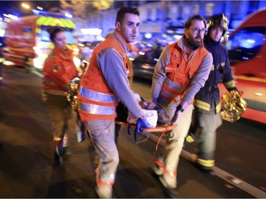 A woman is being evacuated from the Bataclan theater after a shooting in Paris, Friday Nov. 13, 2015.  French President Francois Hollande declared a state of emergency.