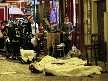 A woman watches victims in the 10th district of Paris, Friday, Nov. 13, 2015.  At least 35 people were killed Friday in shootings and explosions around Paris, many of them in a popular concert hall where patrons were taken hostage, police and medical officials said.