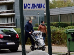 People walk past in the vicinity of a police intervention to arrest people in connection with the deadly attacks inParis, in Brussels' Molenbeek district, on November 15, 2015. Five people were arrested in connection with the November 13 deadly attacks in Paris in the Molenbeek district in Brussels, according to officials.