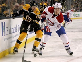 Boston Bruins' Brett Connolly (14) and Montreal Canadiens' David Desharnais (51) battle for the puck along the boards during the second period of an NHL hockey game in Boston, Saturday, Oct. 10, 2015.