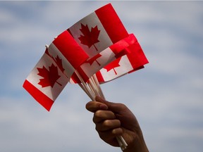 A volunteer waves Canadian flags while handing them out to people during Canada Day festivities in Vancouver, B.C., on Monday, July 1, 2013.