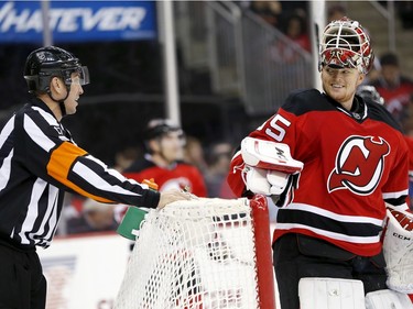 New Jersey Devils goalie Cory Schneider, right, talks to referee Frederick L'Ecuyer during the first period of an NHL hockey game against the Montreal Canadiens, Friday, Nov. 27, 2015, in Newark, N.J.