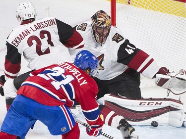 Arizona Coyotes goaltender Mike Smith makes a save against Montreal Canadiens' Devant Smith-Pelly as Coyotes' Oliver Ekman-Larsson defends during second period NHL hockey action in Montreal, Thursday, November 19, 2015.