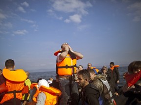 In this Saturday, Oct. 3, 2015 file photo, Syrian refugee Mahmoud Naoura, 30, center, chants "Thanks God we are safe,"while standing on a dinghy arriving from the Turkish coast to the northeastern Greek island of Lesbos. Bold ideas for helping Syrian refugees and their overburdened Middle Eastern host countries are gaining traction among international donors who were shocked into action by this year's migration of hundreds of thousands of desperate Syrians to Europe.