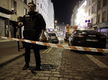 A policeman stands behind a cordon blocking the street near the site of an attack in a restaurant in Paris on November 13, 2015. At least 18 people were killed in multiple attacks in Paris Friday, including one near the Stade de France sports stadium and another at a concert venue.