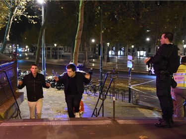Two men evacuate the Place de la Republique square in Paris as a police officer looks on, after several shootings on November 13, 2015.