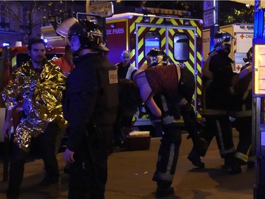 Rescuers workers evacuate a woman near the Bataclan concert hall in central Paris, on November 13, 2015. A number of people were killed and others injured in a series of gun attacks across Paris, as well as explosions outside the national stadium where France was hosting Germany.