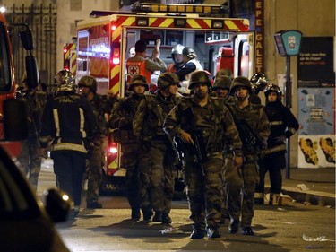 Soldiers walk in front of an ambulance as rescue workers evacuate victims near La Belle Equipe, rue de Charonne, at the site of an attack on Paris on November 14, 2015 after a series of gun attacks occurred across Paris as well as explosions outside the national stadium where France was hosting Germany. More than 100 people were killed in a mass hostage-taking at a Paris concert hall and many more were feared dead in a series of bombings and shootings, as France declared a national state of emergency.