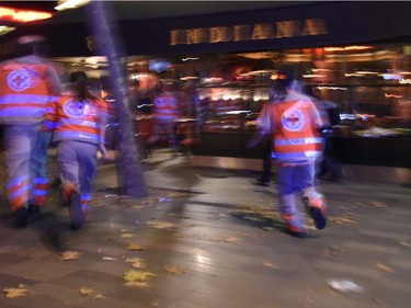 Rescue workers run after hearing what is believed to be explosions or gun shots near Place de la Republique square in Paris on November 13, 2015.