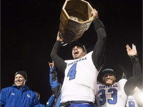 Carabins quarterback Gabriel Cousineau raises the Dunsmore Cup after beating the Laval Rouge et Or in the RSEQ final on Nov. 14, 2015, in Quebec City. Coach Danny Maciocia, left, and teammate Nicholas Narbonne-Bourque, right, celebrate.
