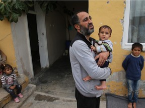 In this picture taken on Friday, Oct. 23, 2015, Syrian refugee Anwar Ahmad Abdullah, 42, holds his son Abdul-Muneim, 10 months, at their unfurnished home, in the Turkish-Syrian border city of Reyhanli, southern Turkey. Abdullah fled with his family from the central Syrian town of Palmyra, which was captured over the summer by the Islamic State group and has been targeted in the Russian campaign. They fled to the Islamic State group's de facto capital, the Syrian city of Raqqa. There, a school where they were staying was hit in a strike, so they fled again, making their way to Turkey.