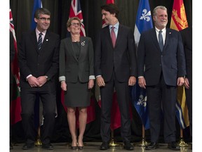 Nova Scotia Premier Stephen McNeil bends his knees to stand at the same height as Ontario Premier Kathleen Wynne as Prime Minister Justin Trudeau and Quebec Premier Philippe Couillard look at a First Ministers meeting at the Canadian Museum of Nature in Ottawa on Monday, Nov. 23, 2015. From proposed changes in voting system to the economy, Ottawa's relationship with the provinces can be expected to be tested in 2016.