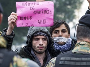 A man holds a placard during a demonstration of migrants waiting to cross the Greek-Macedonian border demonstrate near Gevgelija, Nov. 25, 2015. Macedonia has restricted passage to northern Europe to only Syrians, Iraqis and Afghans.
