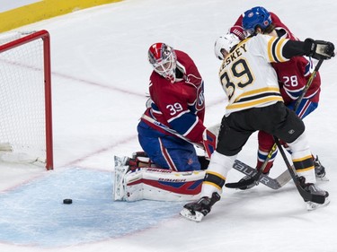 Montreal Canadiens' goalie Mike Condon (39) looks back at a loose puck as defenseman Nathan Beaulieu (28) tries to hold back Boston Bruins' Matt Beleskey (39) during second period NHL hockey action, in Montreal, on Saturday, Nov. 7, 2015.